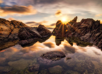 The rock and reflection of kalim beach with sunburst 