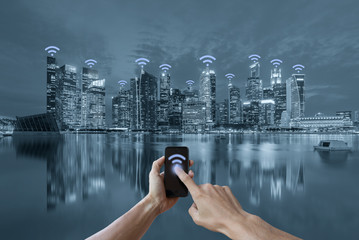 Hands holding smartphone and cityscape wifi network concept