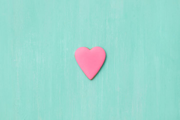 Top view on a little gingerbread cookie in shape of heart on light blue background. Flay layout. Love, Valentines's day concept
