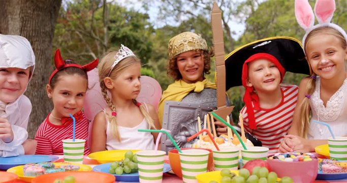 Portrait of group of kids in various costumes having breakfast in the park 4k