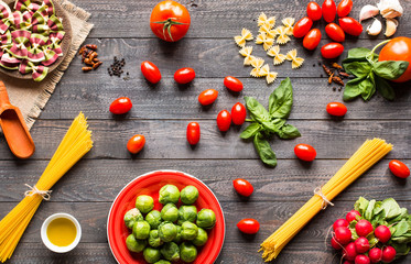 Pasta background. Several types of dry pasta with vegetables over a wooden table.