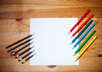 Obraz premium Blank paper and graphite and colorful pencils on the wooden background
