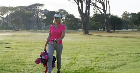 Female golfer walking with golf bag on the golf course 
