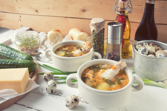 Cheese soup with chicken, herbs and vegetable. Cheese, cucumbers and herbs on wooden table. Light background.