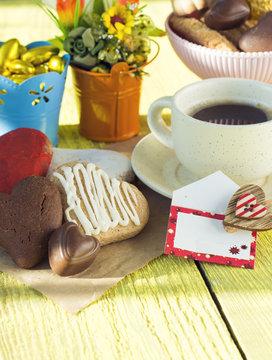 Heart shaped cookies (big and small as couple), cup of coffee, bouquet of flowers decoration. sunny morning. Romantic breakfast or Valentine's Day Breakfast. Toned image 