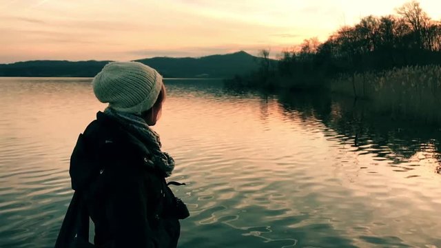 Ragazza al tramonto in riva al lago in slow motion