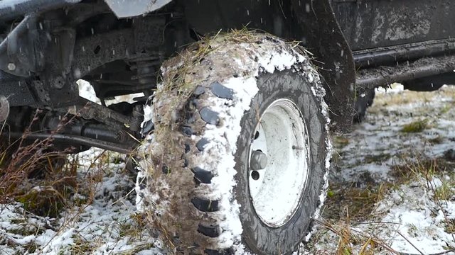 The wheels of the machine with a wide tread all in the snow and grass. HD.