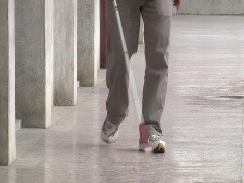 Blind man walking with his white cane for the street 