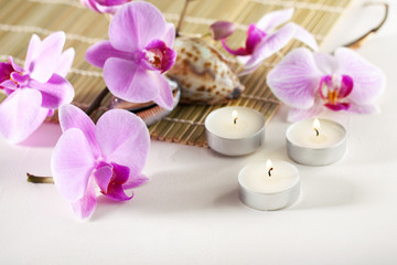 Fototapeta na wymiar Spa still life with aromatic candles, orchid flower sea shells