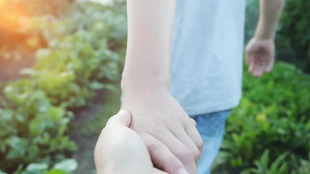 Holding hands of in love couple in green summer forest go together in slowmotion. Sun beams. 1920x1080