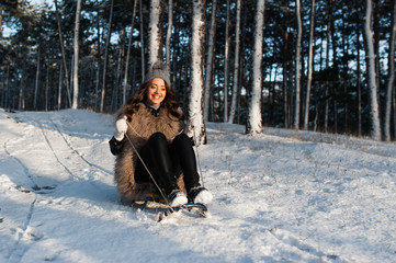 laughing girl in winter clothing goes down on sleds