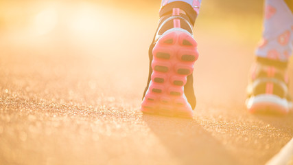 Runner feet running on road closeup on shoe. woman fitness sunri