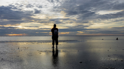 Naklejka premium Silhouette of photographer at the beach during sunset.
