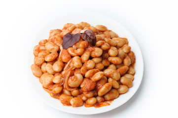 white beans in tomato sauce in a white plate closeup. Isolated