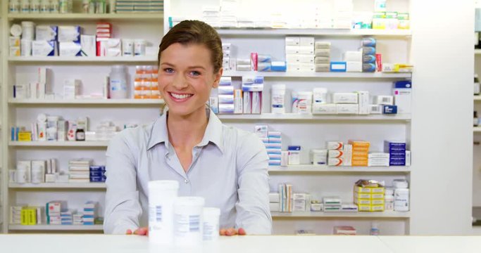 Portrait of pharmacist holding medicine container in pharmacy
