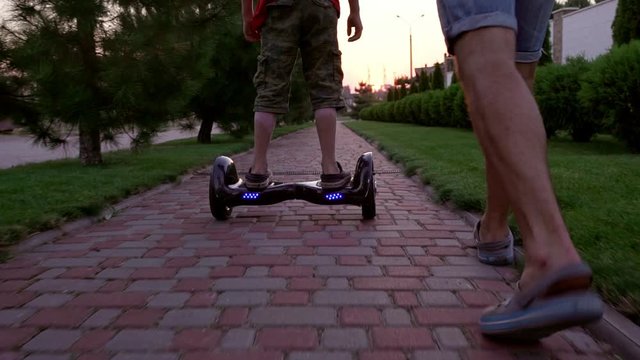 Boy driving gyroscooter outdoors with father walking near him while in slowmotion