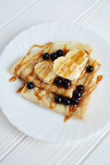 Pancakes with berries and banana on a white background