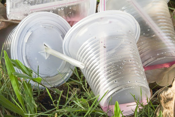 Fototapeta na wymiar Bad enviromental habit of improper disposal of non-biodegradable PVC cups with straw in public park