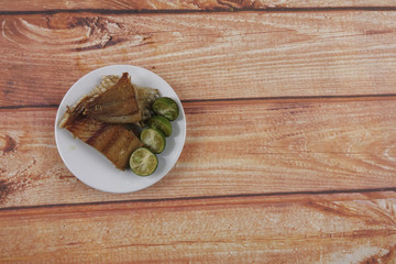 Salted fish with lime on wooden background.