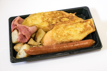 The close up of delicious breakfast set on black plastic tray. (becon, sausage, potato, omelette) 