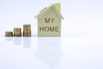 Wooden house model with pile of coin and calculator. House finance concept.