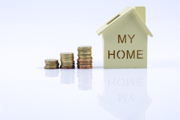 Wooden house model with pile of coin and calculator. House finance concept.