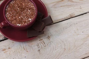 Milk chocolate in a cup on a saucer on a wooden background. Clos