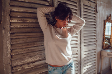 Beautiful young womanl dressed in blank sweatshirt standing on wood wall background. Mock-up.