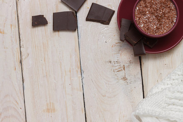 Milk chocolate in a cup on a saucer on a light wooden background