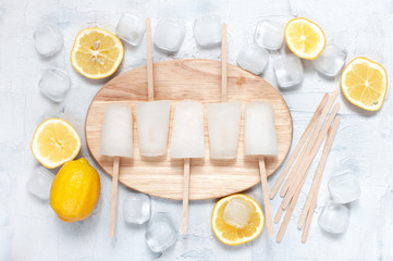 Lemon lollies, lemons and ice cubes on the board