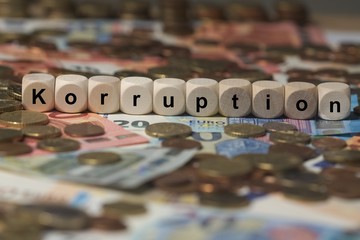 korruption - Holzwürfel mit Buchstaben im Hintergrund mit Geld, Geldscheine