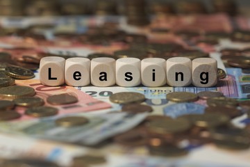 leasing - Holzwürfel mit Buchstaben im Hintergrund mit Geld, Geldscheine
