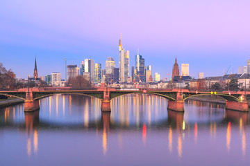 Fototapeta na wymiar Picturesque view of Frankfurt am Main skyline and Ignatz Bubis Brucke bridge at sunrise with mirror reflections in the river, Germany