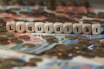 liquidität - Holzwürfel mit Buchstaben im Hintergrund mit Geld, Geldscheine - obrazy, fototapety, plakaty