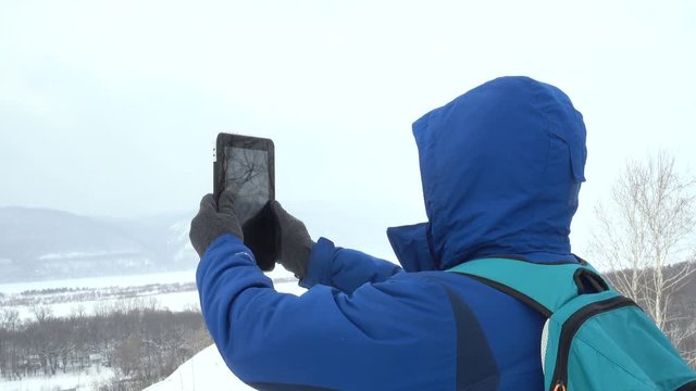 Traveler With a Beard Using Tablet On Mountain. Caucasian Men in Jacket looking for a GPS Signal. Mountaineer Winter Mobile Communications.Adventure Expedition Man Talk Cell Men Call Accident