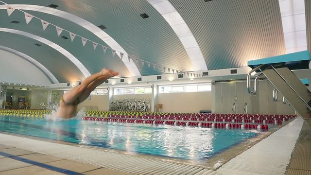 The swimmer in slowmotion jumps from the diving board in the swimming pool