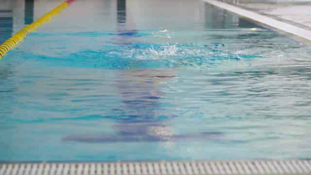 Sports woman in goggles swims under the water in the swimming pool