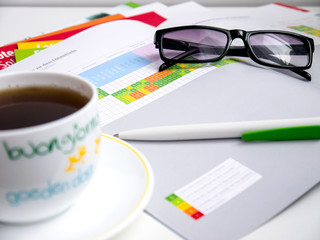 Financial document tables and charts, glasses, Cup of tea on the table