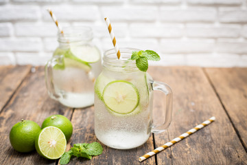 Homemade lemonade drink with fresh lime in glass on old wooden background