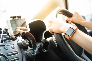 Hands of female with smart watch using GPS and driving car.
