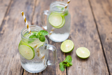 Homemade lemonade drink with fresh lime in glass on old wooden background