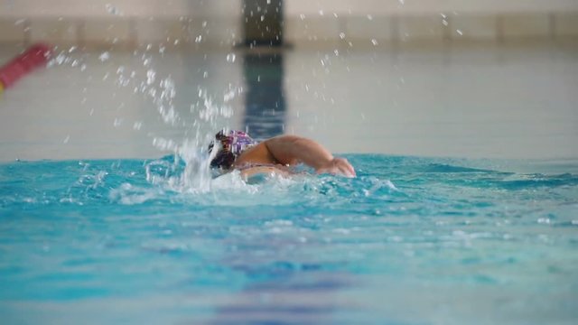 The woman in slowmotion swimming breaststroke in the swimming pool