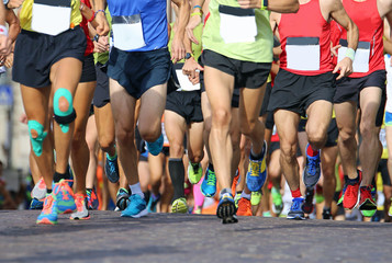 Fototapeta na wymiar muscular legs of a large number of runners during sports race