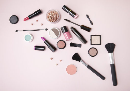 Make up products arranged on a light pink background