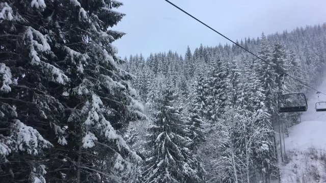 Chair lift on ski resort. Empty sits among the trees covered with snow