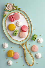 Flat lay of french macarons and meringues on a vintage frame. Top view