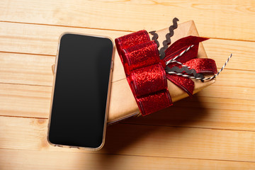 Smart phone and gift on wooden background