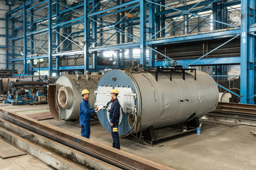 Experienced worker checking the quality of manufactured boilers