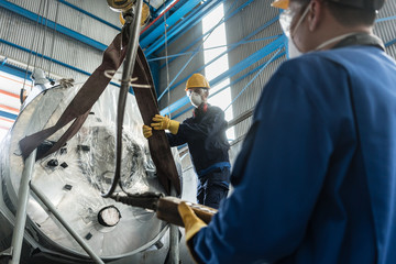 Workers handling equipment for lifting industrial boilers