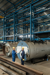 Experienced worker checking the quality of manufactured boilers